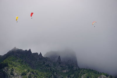 People paragliding over mountain against sky