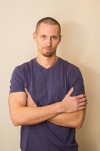 Portrait of young man standing against wall