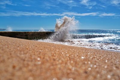 Sea waves splashing on shore against sky