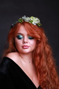 Sensuous young woman wearing wreath against black background