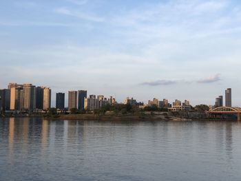 Sea by buildings against sky in city