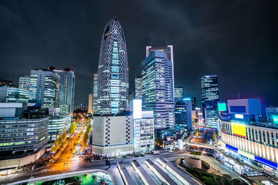 Illuminated modern buildings in city against sky at night