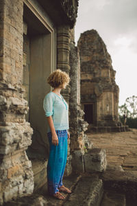 Side view of mid adult woman standing at angkor wat entrance