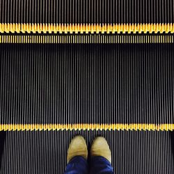 Low section of person standing on escalator