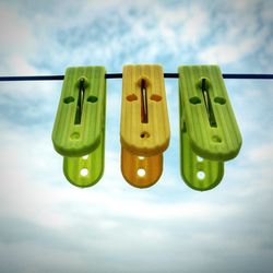 Low angle view of clothespins on rope against sky