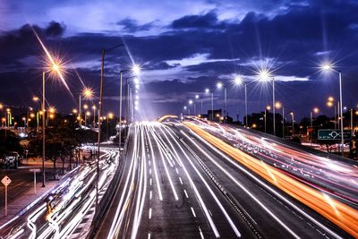 Light trails on city street against sky at night