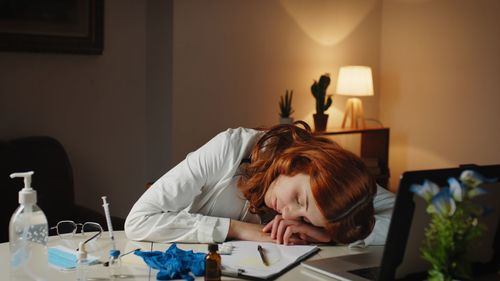 Young female doctor sleeps on the hospital desk tired of the shift