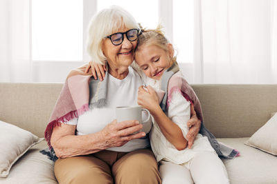 Portrait of mother and daughter sitting on sofa at home