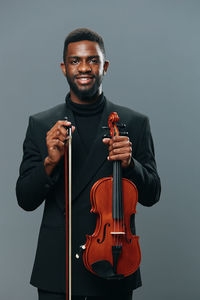 Portrait of man playing violin against gray background