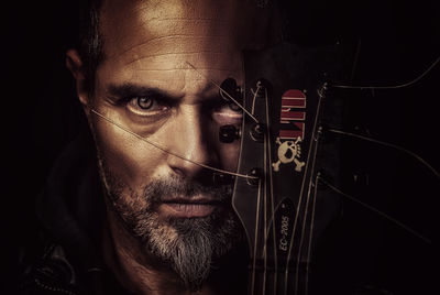 Close-up portrait of man wearing sunglasses against black background