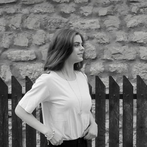 Young woman looking away against wall