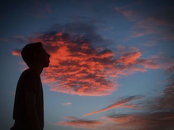 Silhouette man standing against dramatic sky during sunset