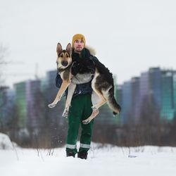 Portrait of man holding dog during winter