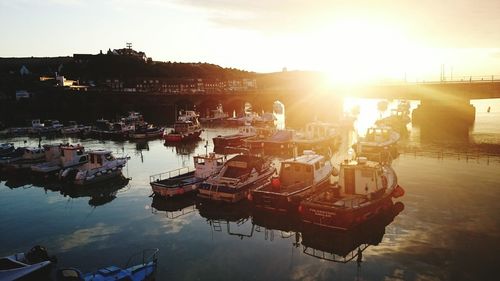 Boats moored in calm lake at sunset