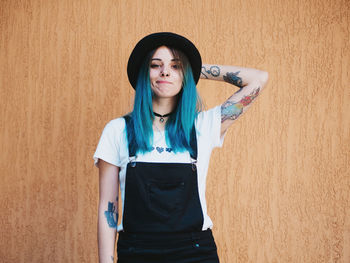 Portrait of young woman standing against wall