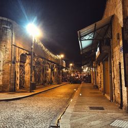 Illuminated street amidst buildings at night