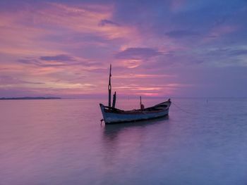 Fishing boat in sea against sky during sunset