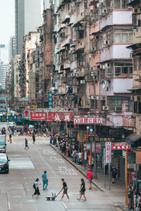 People on street against buildings in city