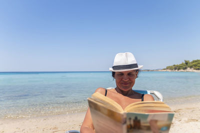 Portrait of a happy woman sitting on a deckchair and reading a book. happy woman on the beach 