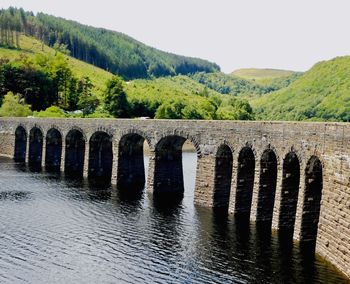 Arch bridge over river against sky