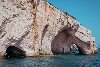 Rock formation in sea against clear sky