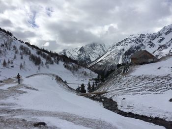 Rear view of hiker amidst snowcapped mountains against sky