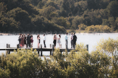 People standing on pier over lake