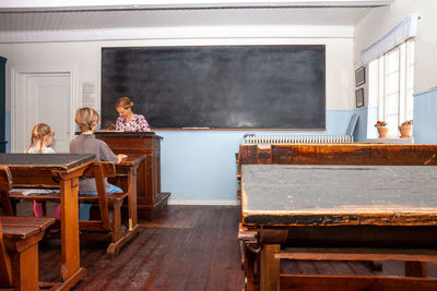 Teacher with students sitting on bench in classroom