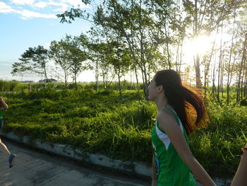 Side view of woman standing on land against trees