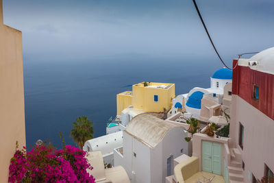 Buildings by sea against blue sky