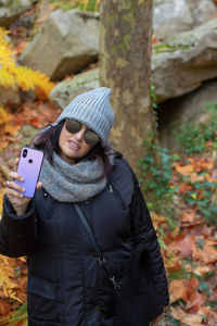 Portrait of a woman with sunglasses and wool hat taking self-portraits with smartphone 