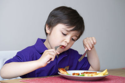 Cute boy eating food at home