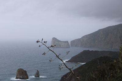 Scenic view of sea by mountains against sky