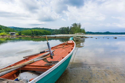 Boat moored at lake against sky