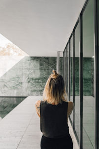 Rear view of woman standing by window