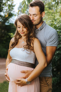 Husband embracing pregnant wife outdoors