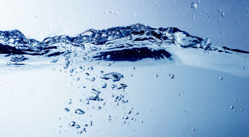 Close-up of waterdrops on glass against blue background