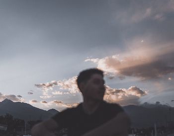 Rear view of silhouette man standing on mountain against sky