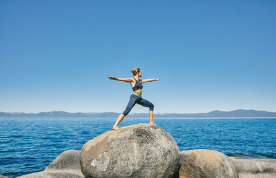 Young woman practicing yoga on lake tahoe in northern california.