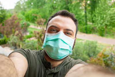 Portrait of man wearing mask standing against trees