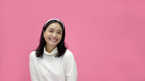 Portrait of young woman standing against yellow background