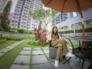 Portrait of smiling woman sitting on sidewalk