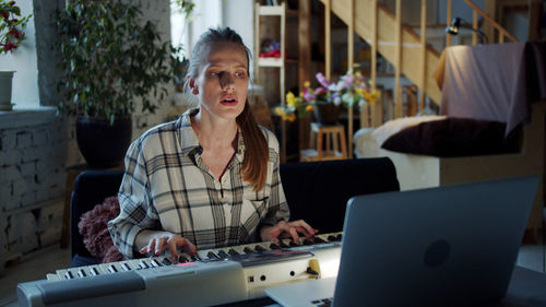 Woman learning piano from laptop