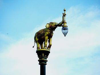 Low angle view of statue of street light against sky