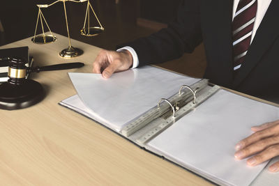 Midsection of man reading book on table