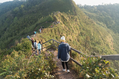 Rear view of hikers walking on mountain by railing