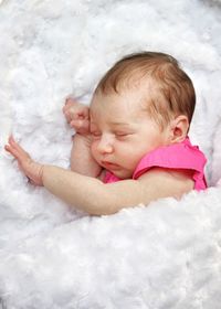 Portrait of cute sleeping newborn baby girl on fluffy white blanket 