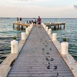 People on pier over sea against sky