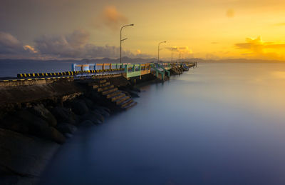 Pier over sea against sky during sunset