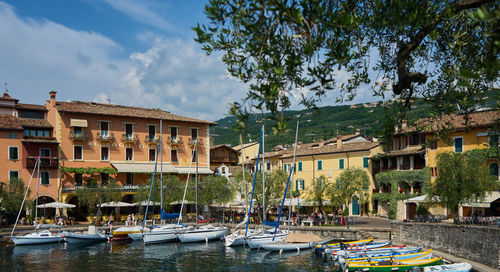 Boats moored in canal by buildings against sky